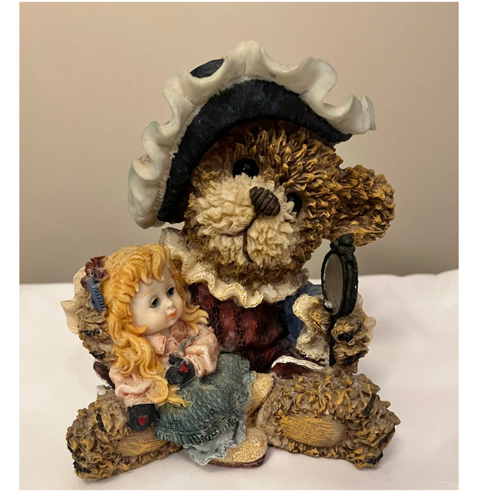 Bear with a fancy hat holding a little girl looking at‎ a mirror
